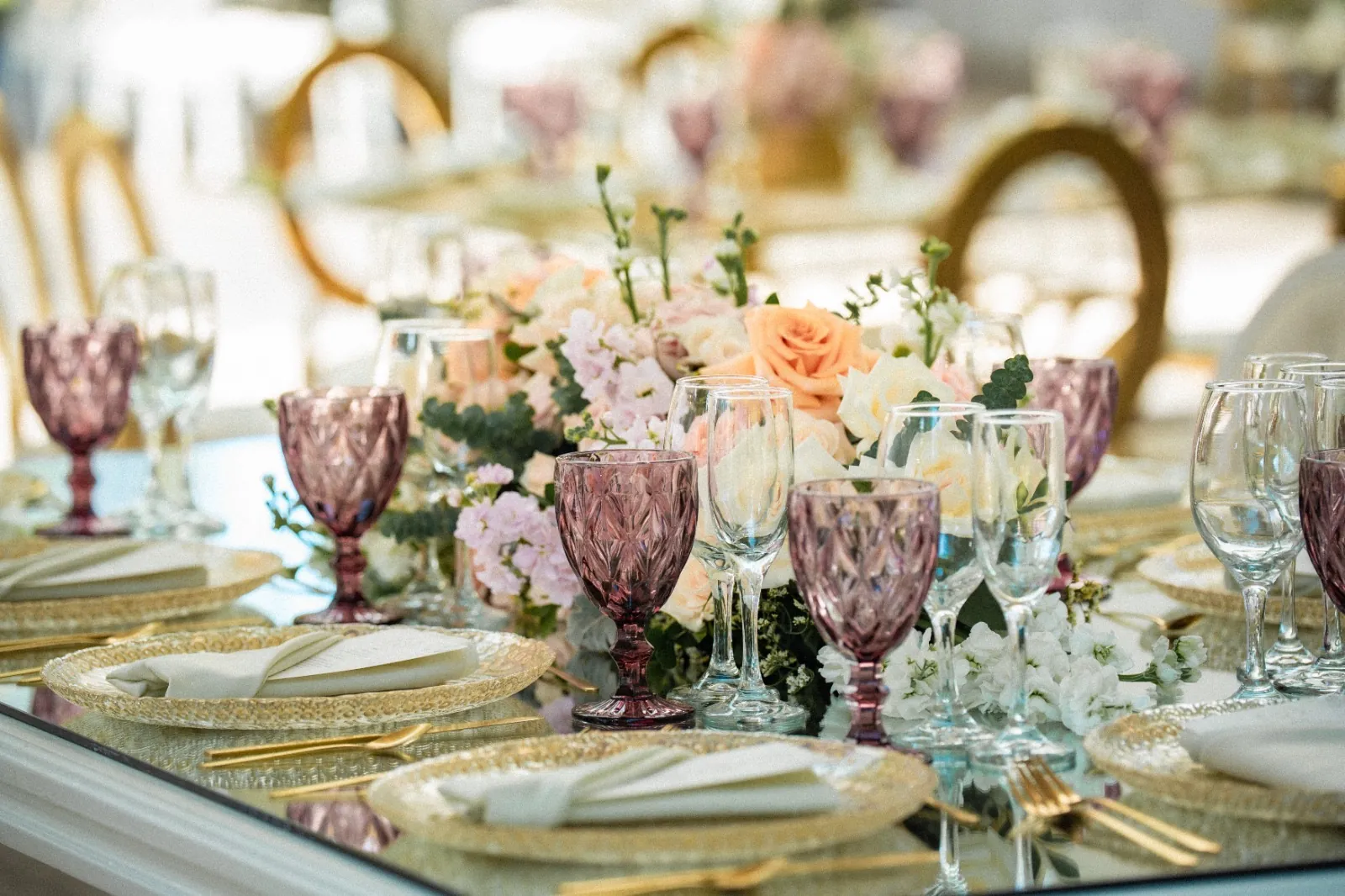Detalle de puesto con copas en palo de rosa y vajilla dorada en la boda de Daya y Marco