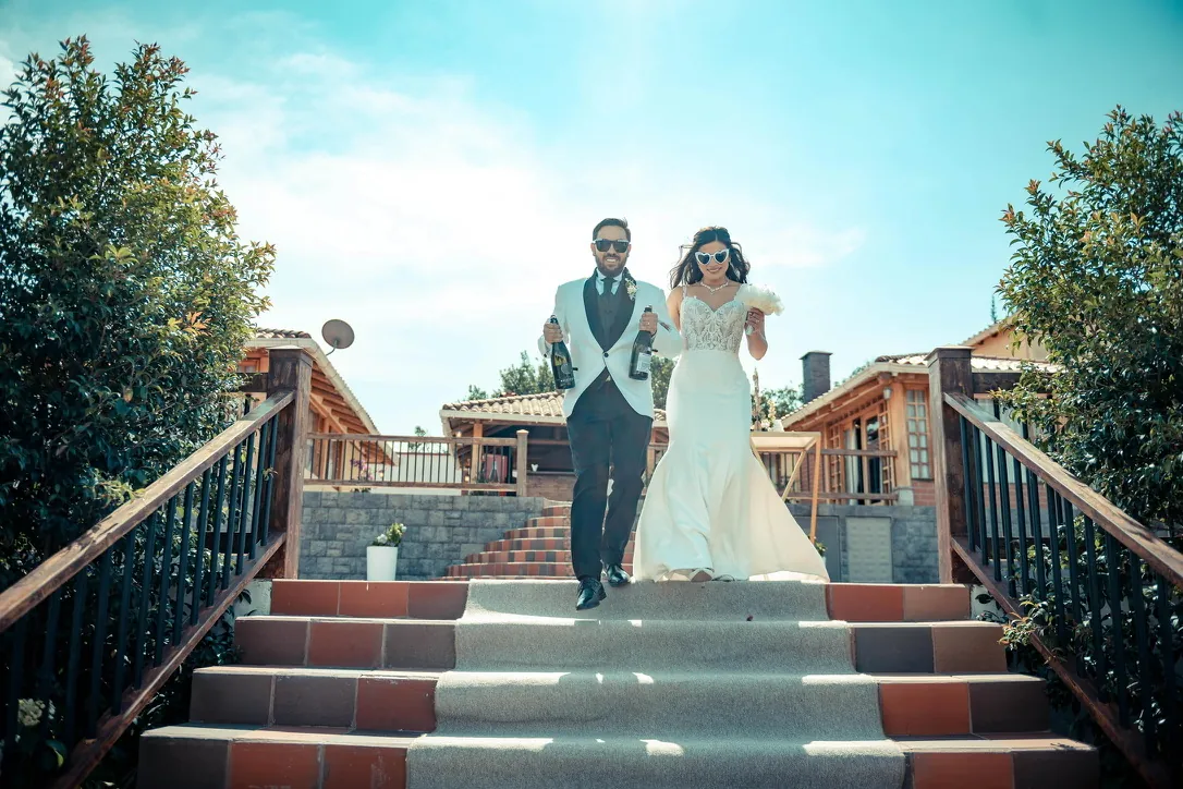 Novios bajando las escalinatas de Villa Lagos con botellas de champagne, Puembo