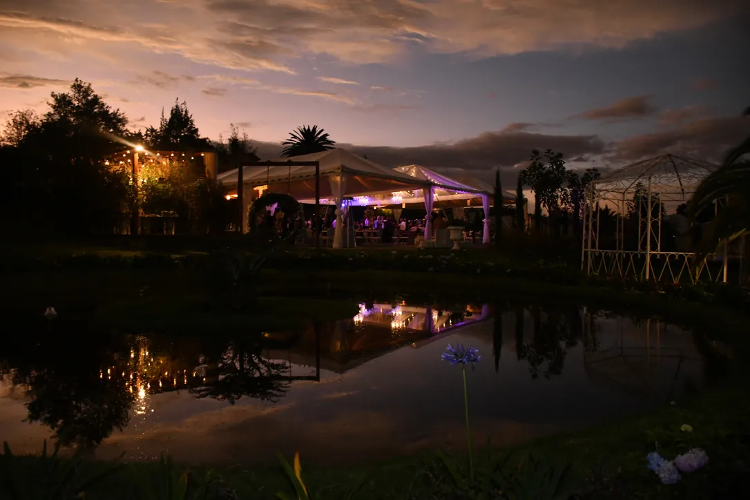 Estanque de Villa Lagos al atardecer con el reflejo de la carpa iluminada, Puembo, Quito