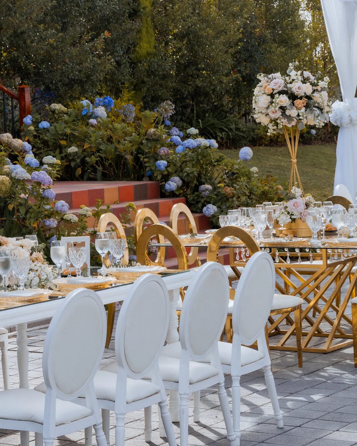 Combinación de mesas de madera y vidrio junto a los jardines de hortensias de Villa Lagos